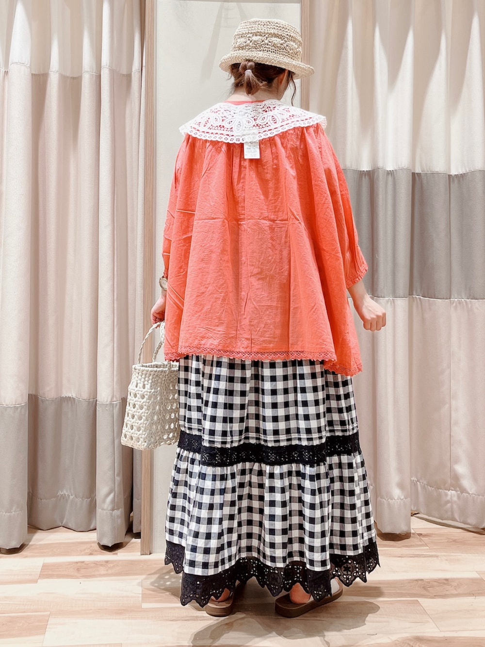 レッド系のシャツ/ブラウス、ブラック系のスカート、ホワイト系のハンドバッグを着用したレディースの夏コーディネートの2枚目の写真