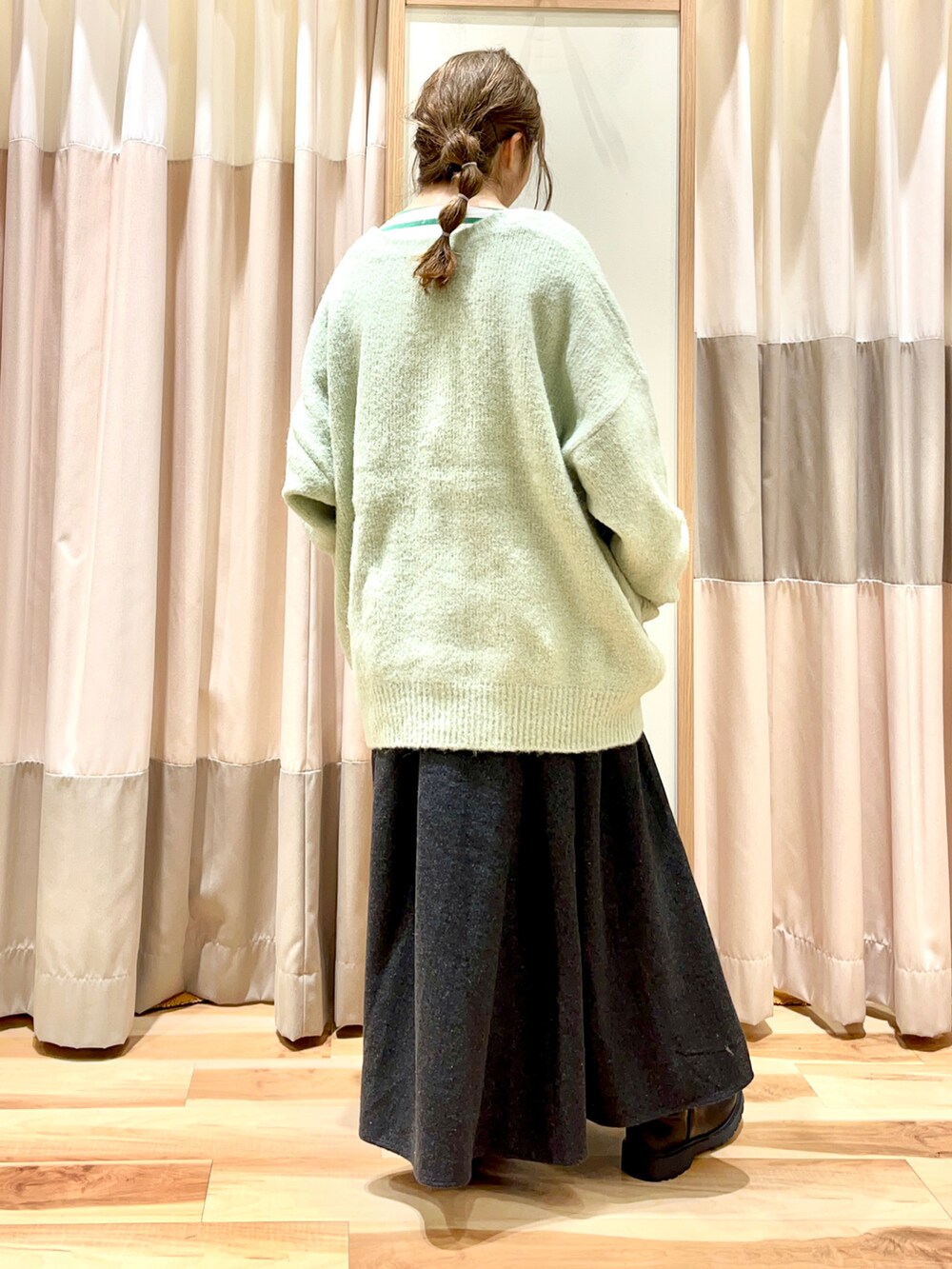 グリーン系のTシャツ/カットソー、グリーン系のカーディガン/ボレロ、グレー系のスカートを着用したレディースの冬コーディネートの2枚目の写真