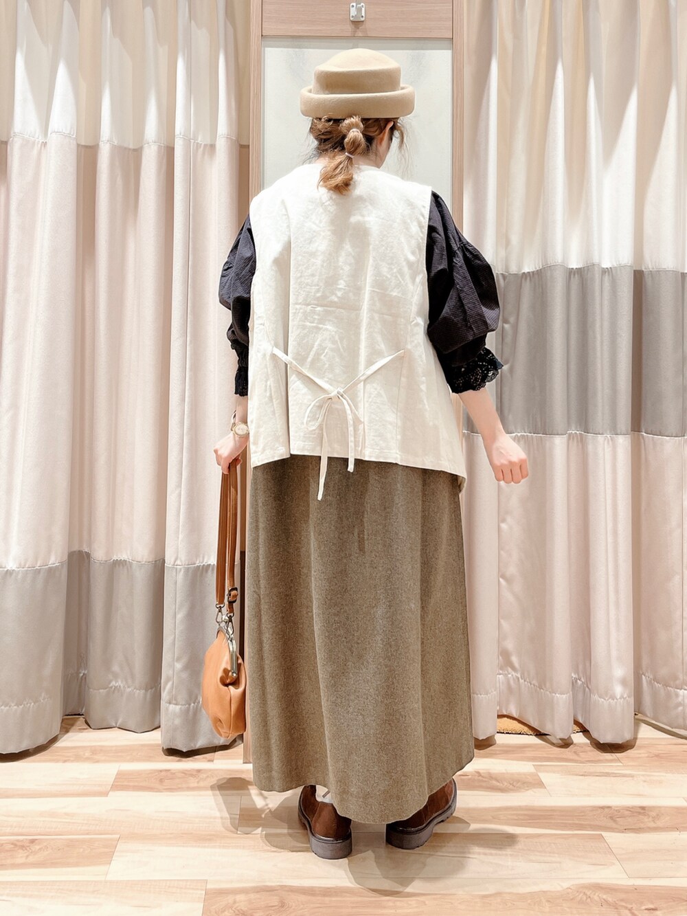 グレー系のシャツ/ブラウス、ホワイト系のベスト、ブラウン系のワンピースを着用したレディースの秋コーディネートの2枚目の写真