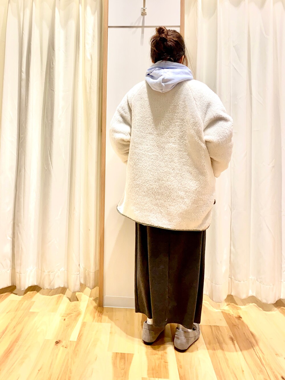 ブルー系のパーカー、グレー系のスカート、グリーン系のノーカラージャケットを着用したレディースの冬コーディネートの2枚目の写真