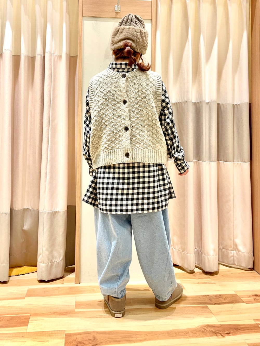 ベージュ系のベスト、ブラック系のチュニック、ブルー系のデニムパンツを着用したレディースの冬コーディネートの2枚目の写真