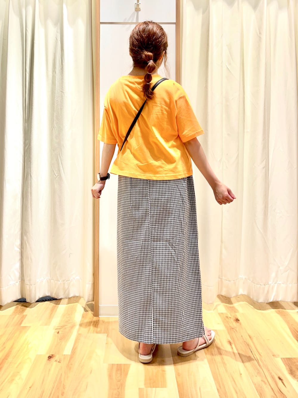 オレンジ系のTシャツ/カットソー、ブラック系のスカート、ブラック系のショルダーバッグを着用したレディースの夏コーディネートの2枚目の写真