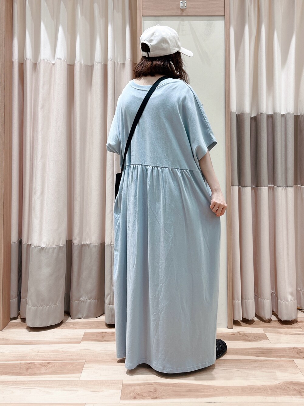 ブルー系のワンピース、ブラック系のハンドバッグ、ブラック系のサンダルを着用したレディースの春コーディネートの2枚目の写真