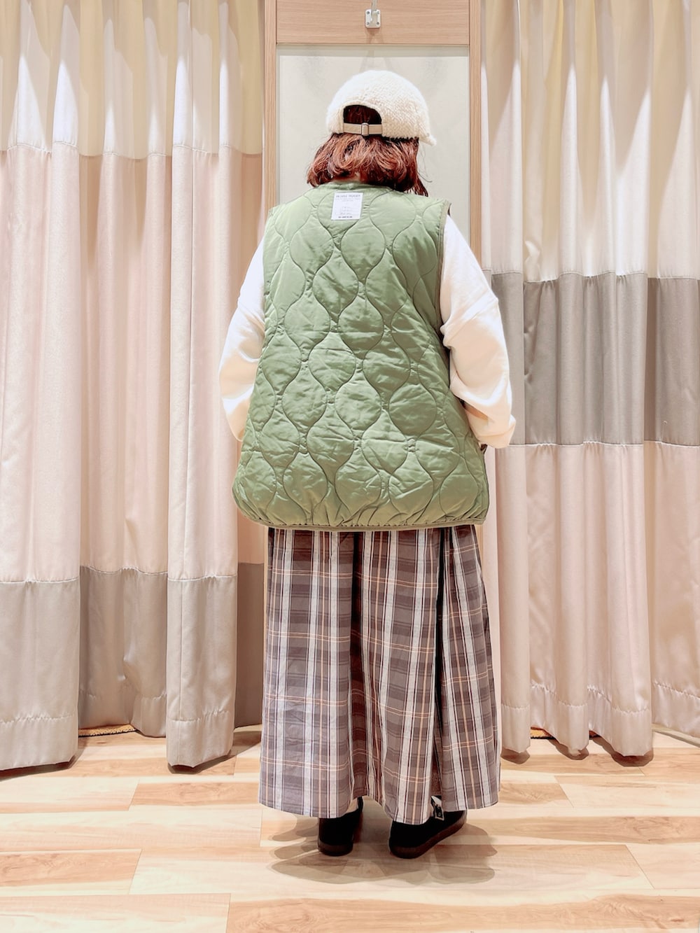 ホワイト系のTシャツ/カットソー、グリーン系のベスト、グレー系のスカートを着用したレディースの秋コーディネートの2枚目の写真