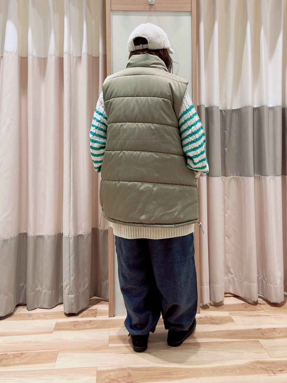 グリーン系のニット/セーター、ベージュ系のベスト、ブルー系のカーゴパンツを着用したレディースの冬コーディネートの2枚目の写真