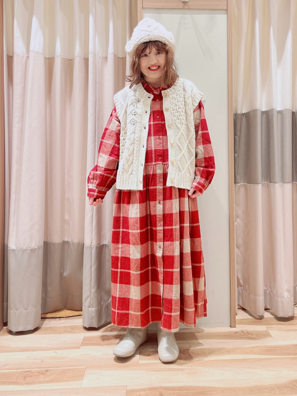 ホワイト系のベスト、レッド系のワンピース、ホワイト系のブーツを着用したレディースの冬コーディネートの3枚目の写真