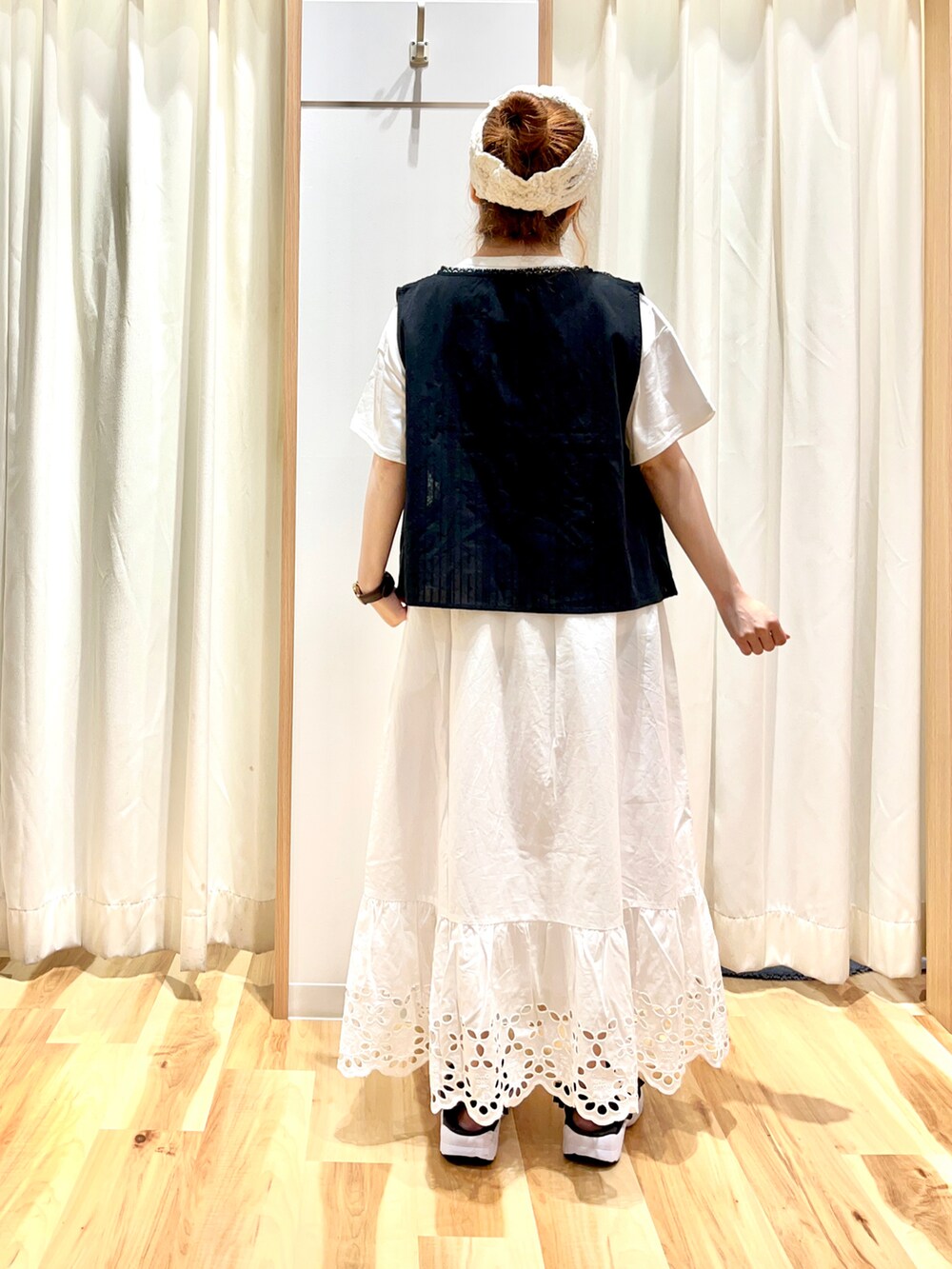 ブラック系のベスト、ホワイト系のTシャツ/カットソー、ホワイト系のスカートを着用したレディースの夏コーディネートの2枚目の写真