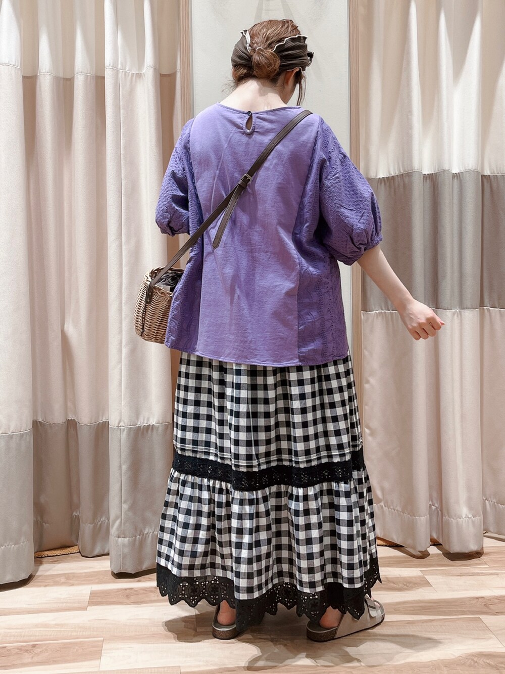 パープル系のTシャツ/カットソー、ブラック系のスカート、ブラウン系のハンドバッグを着用したレディースの夏コーディネートの2枚目の写真