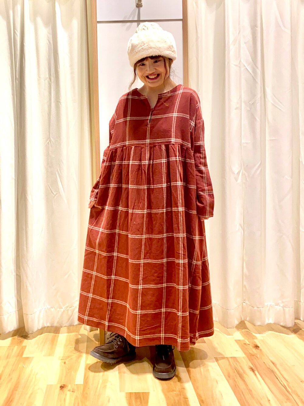 レッド系のワンピース、ホワイト系のカーディガン/ボレロ、ブラウン系のブーツを着用したレディースの冬コーディネートの3枚目の写真