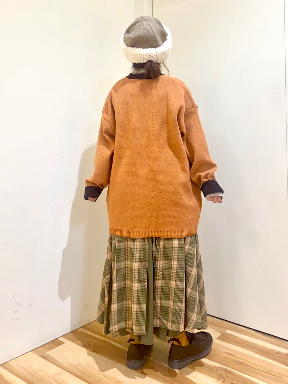 オレンジ系のカーディガン/ボレロ、ベージュ系のTシャツ/カットソー、グリーン系のスカートを着用したレディースの秋コーディネートの2枚目の写真