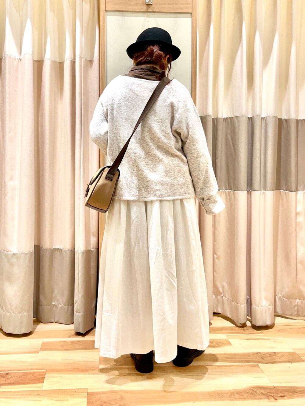 ホワイト系のカーディガン/ボレロ、ブラウン系のチュニック、ホワイト系のスカートを着用したレディースの冬コーディネートの2枚目の写真