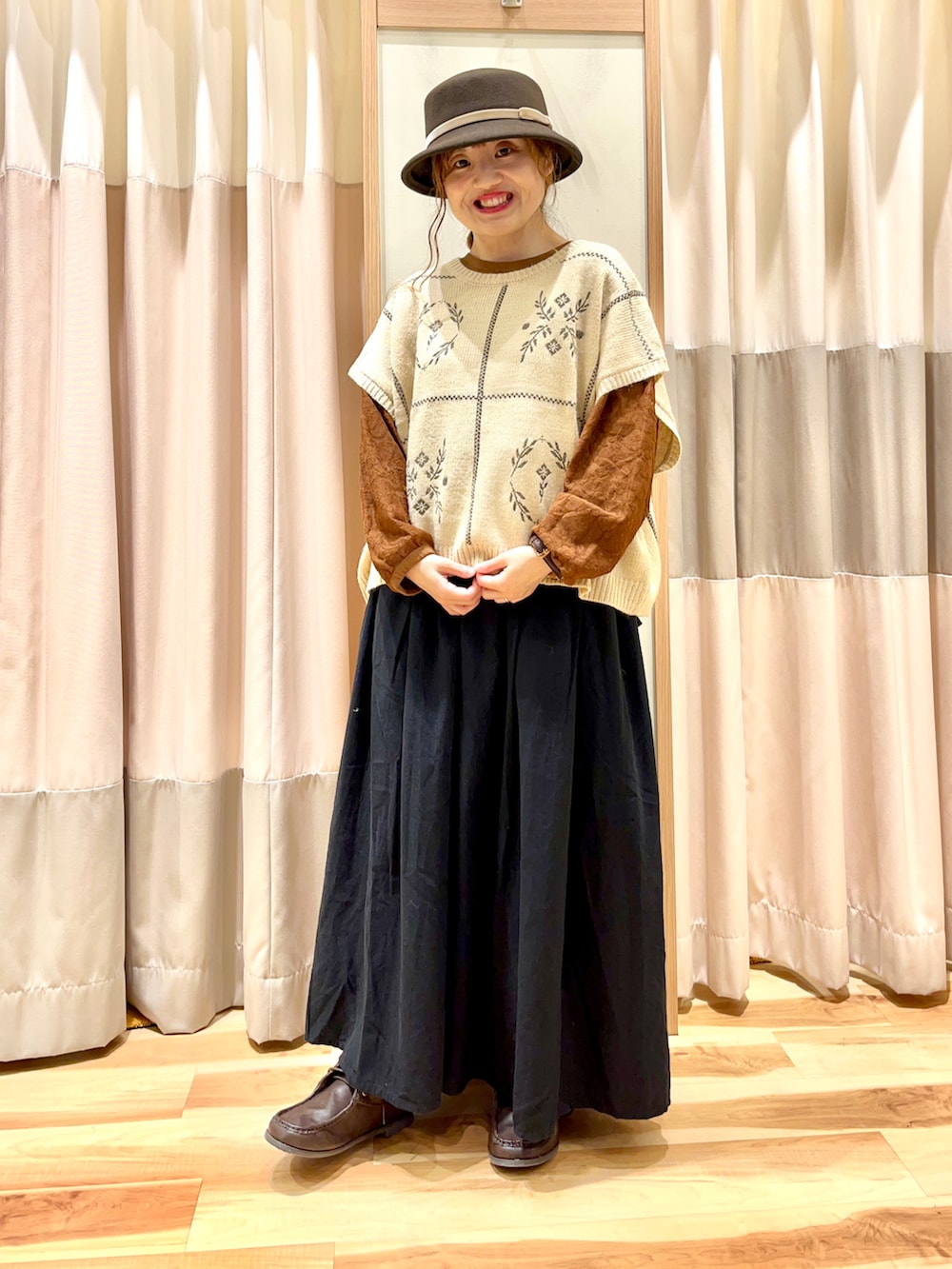 ホワイト系のベスト、ブラウン系のTシャツ/カットソー、ブラック系のスカートを着用したレディースの秋コーディネートの3枚目の写真