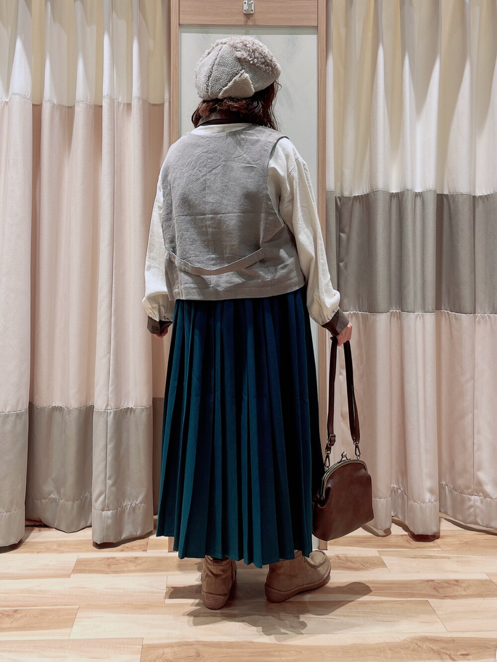 ブラウン系のベスト、ホワイト系のシャツ/ブラウス、グリーン系のスカートを着用したレディースの冬コーディネートの2枚目の写真