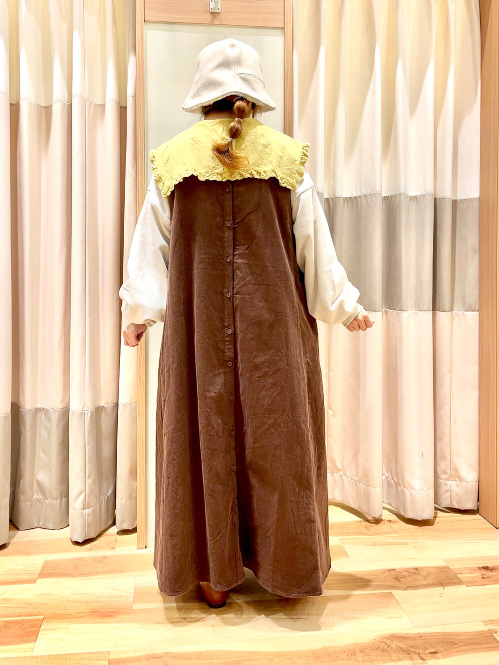 イエロー系のチュニック、ホワイト系のTシャツ/カットソー、ブラウン系のジャンパースカートを着用したレディースの秋コーディネートの2枚目の写真