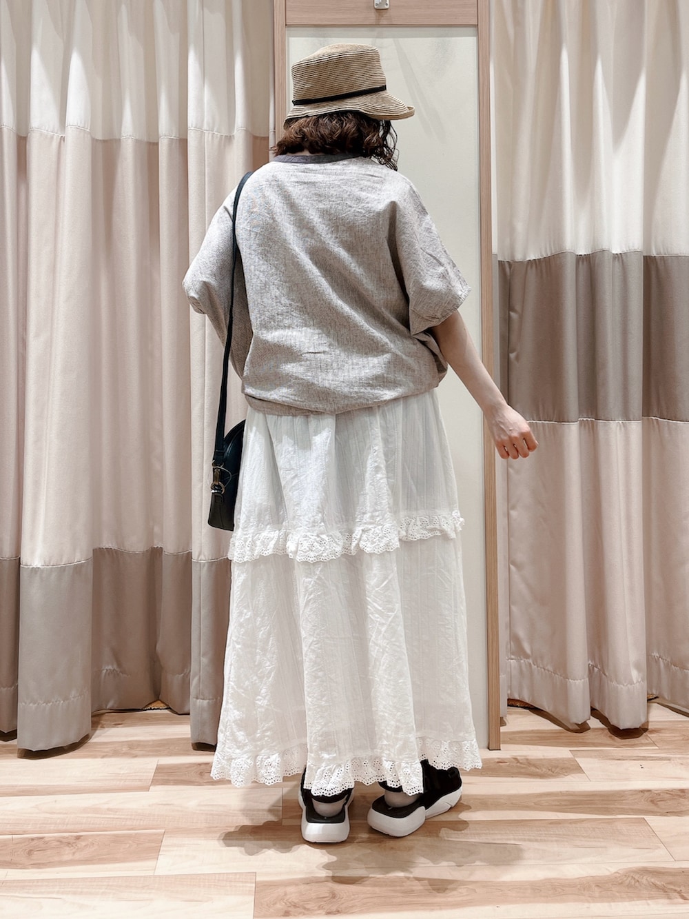 グレー系のシャツ/ブラウス、ホワイト系のスカート、ブラック系のハンドバッグを着用したレディースの夏コーディネートの2枚目の写真