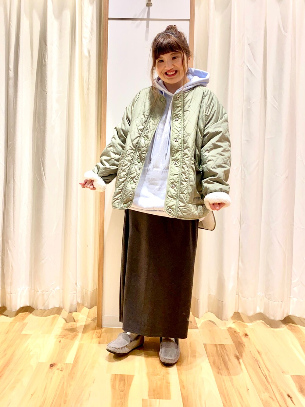 ブルー系のパーカー、グレー系のスカート、グリーン系のノーカラージャケットを着用したレディースの冬コーディネートの4枚目の写真