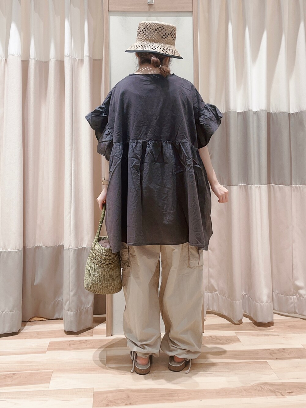 グレー系のチュニック、ベージュ系のカーゴパンツ、グリーン系のハンドバッグを着用したレディースの夏コーディネートの2枚目の写真