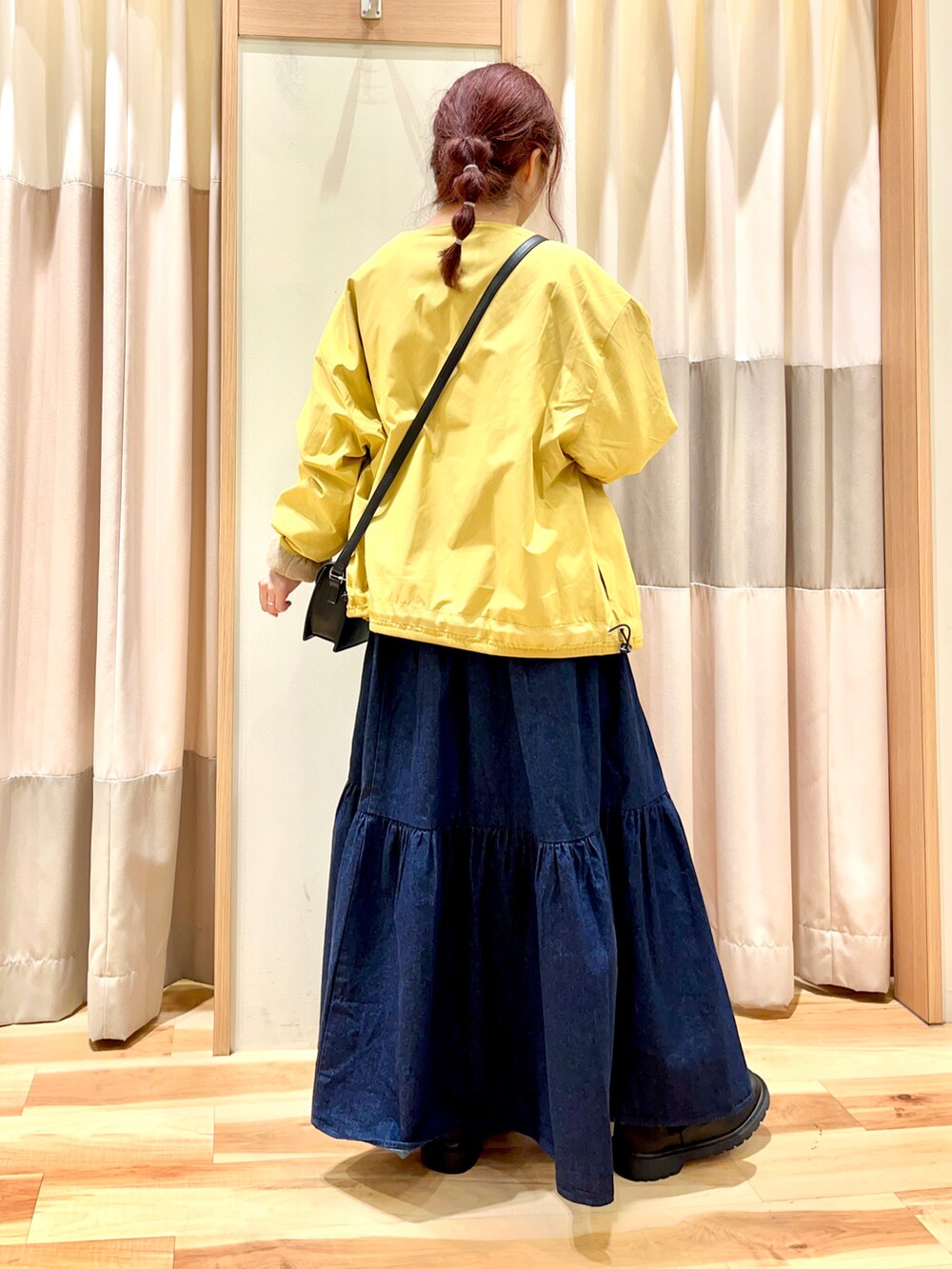 イエロー系のブルゾン、ブラック系のTシャツ/カットソー、ブルー系のデニムスカートを着用したレディースの秋コーディネートの2枚目の写真