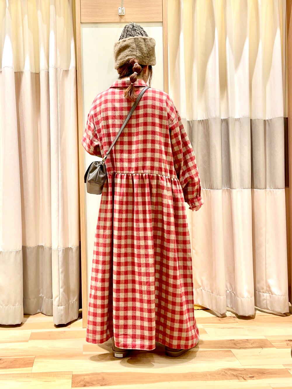 レッド系のシャツワンピース、ブラウン系のショルダーバッグ、ベージュ系のブーツを着用したレディースの冬コーディネートの2枚目の写真