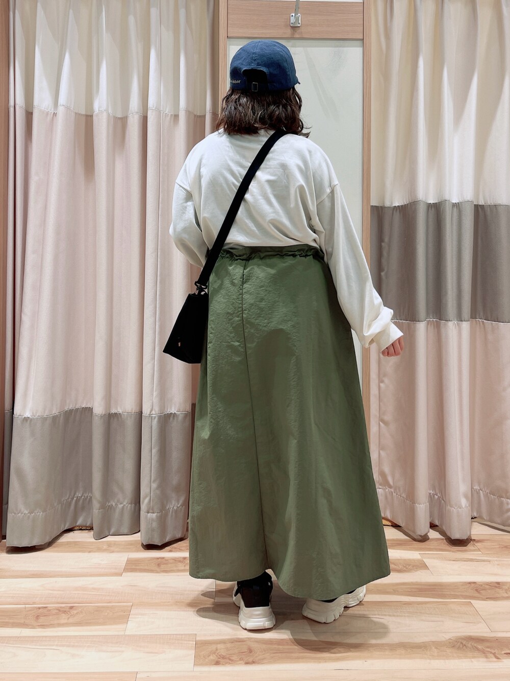 グリーン系のワンピース、ブラック系のハンドバッグ、ブラック系のスニーカーを着用したレディースの春コーディネートの2枚目の写真