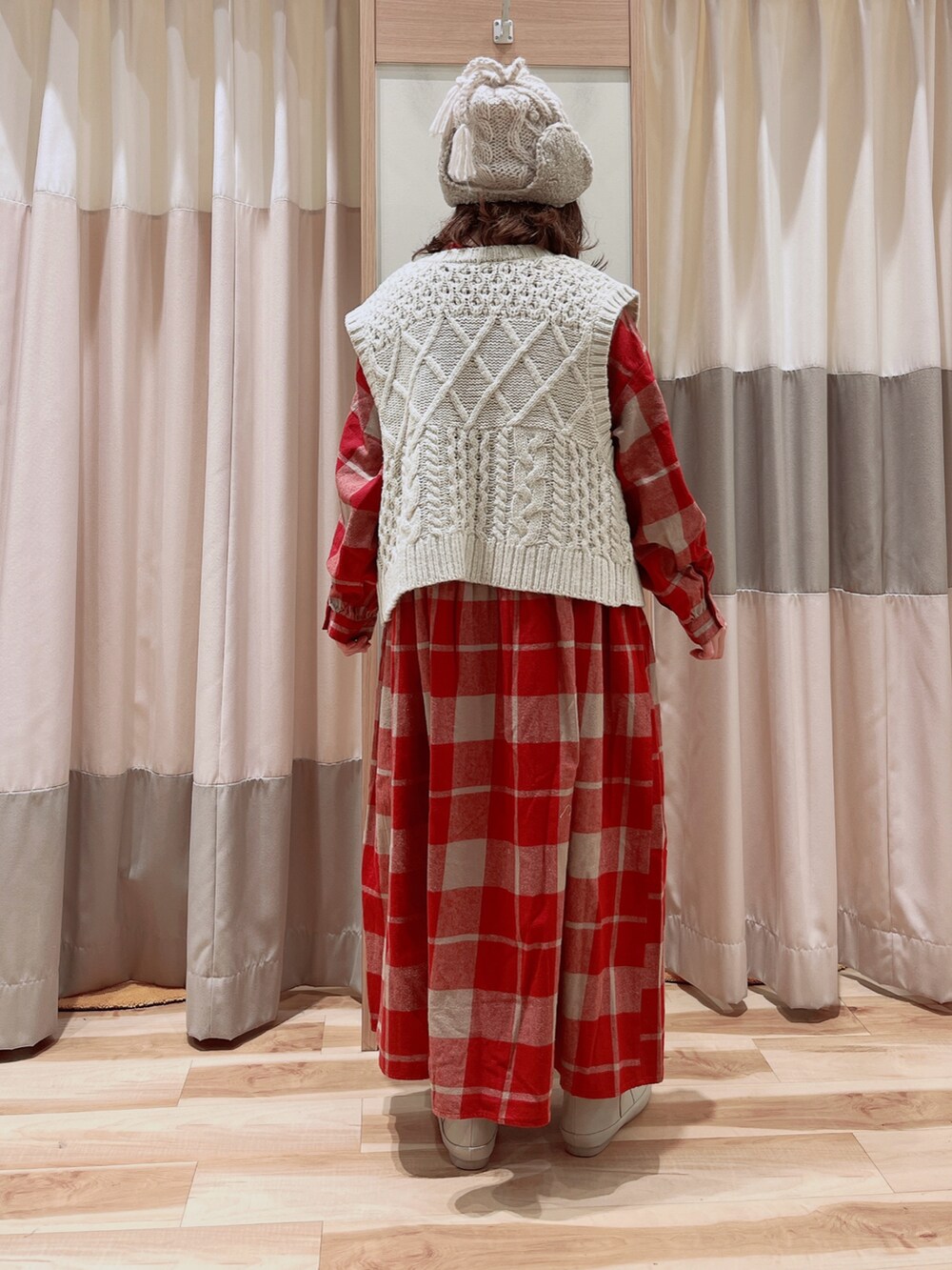 ホワイト系のベスト、レッド系のワンピース、ホワイト系のブーツを着用したレディースの冬コーディネートの4枚目の写真