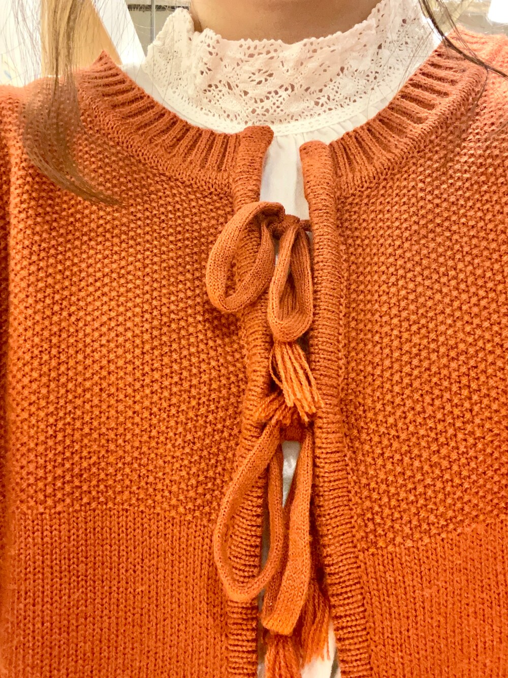 レッド系のカーディガン/ボレロ、ホワイト系のシャツ/ブラウス、オレンジ系のスカートを着用したレディースの冬コーディネートの2枚目の写真