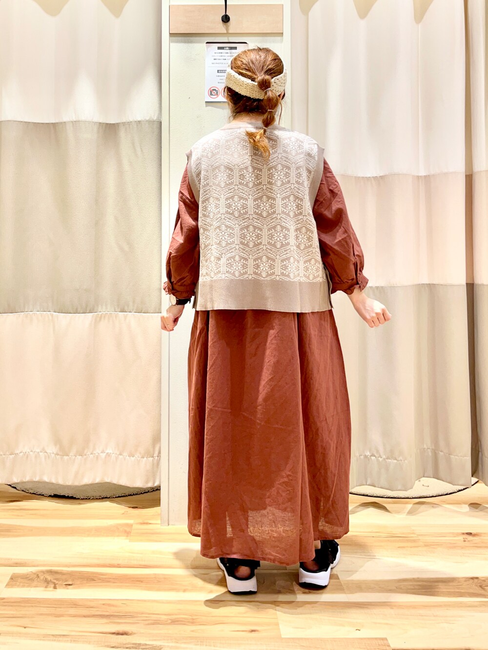 ベージュ系のベスト、ブラウン系のワンピース、ブラック系のサンダルを着用したレディースの秋コーディネートの2枚目の写真