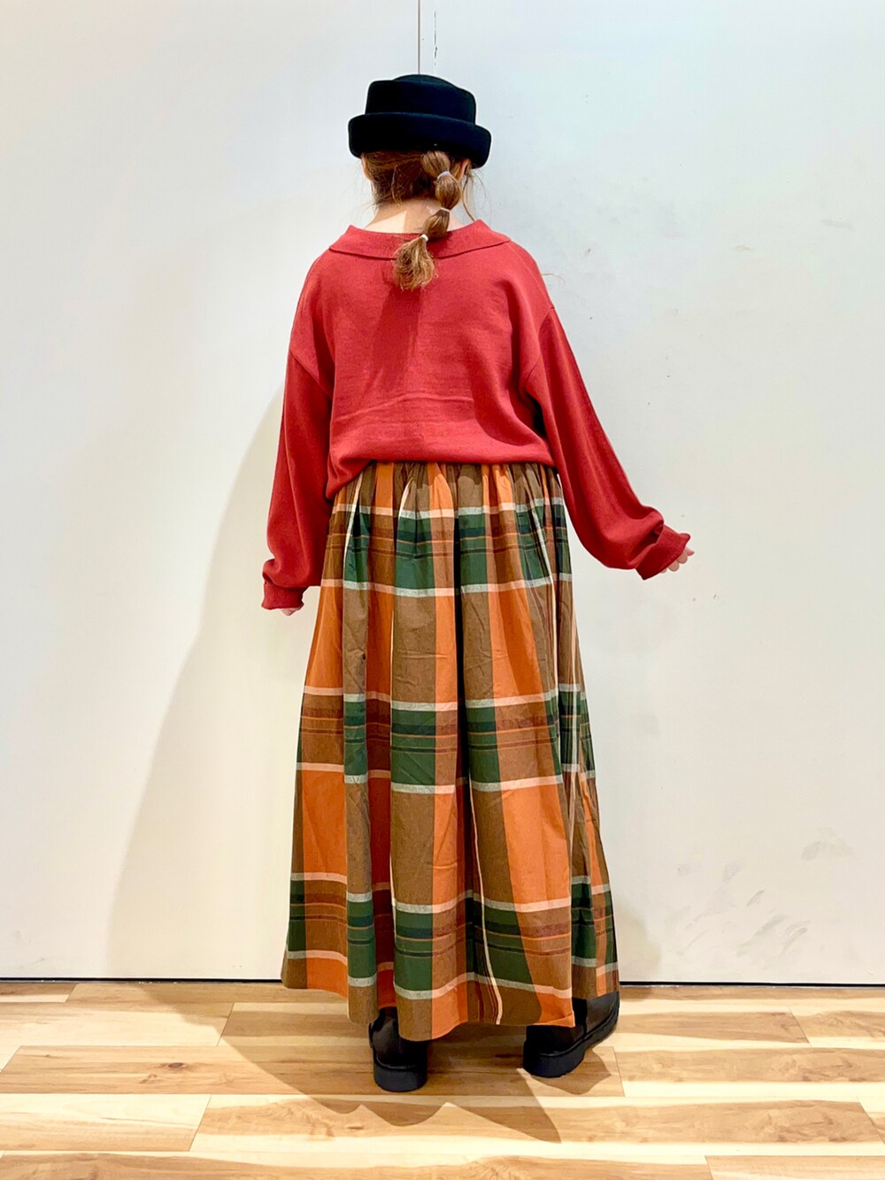 レッド系のカーディガン/ボレロ、オレンジ系のスカート、ブラック系のブーツを着用したレディースの秋コーディネートの2枚目の写真