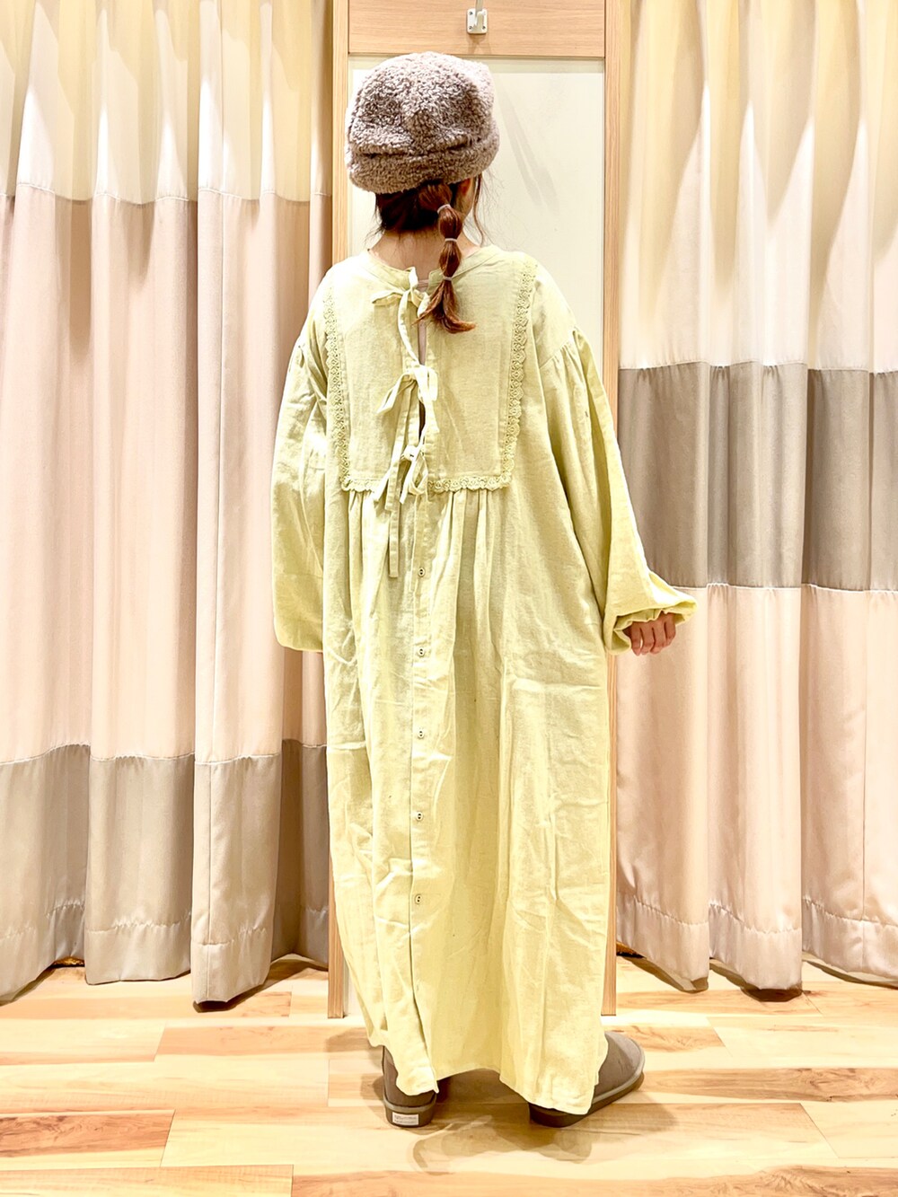 イエロー系のワンピース、ブラウン系のその他アウター、ベージュ系のブーツを着用したレディースの冬コーディネートの4枚目の写真