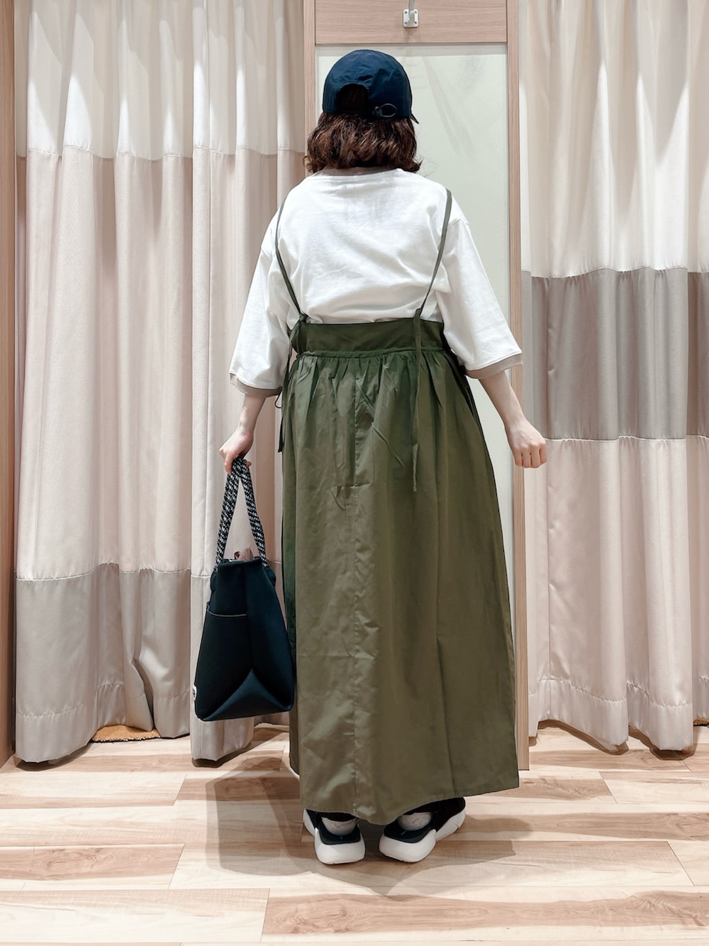 グリーン系のワンピース、ベージュ系のTシャツ/カットソー、ブラック系のハンドバッグを着用したレディースの春コーディネートの2枚目の写真