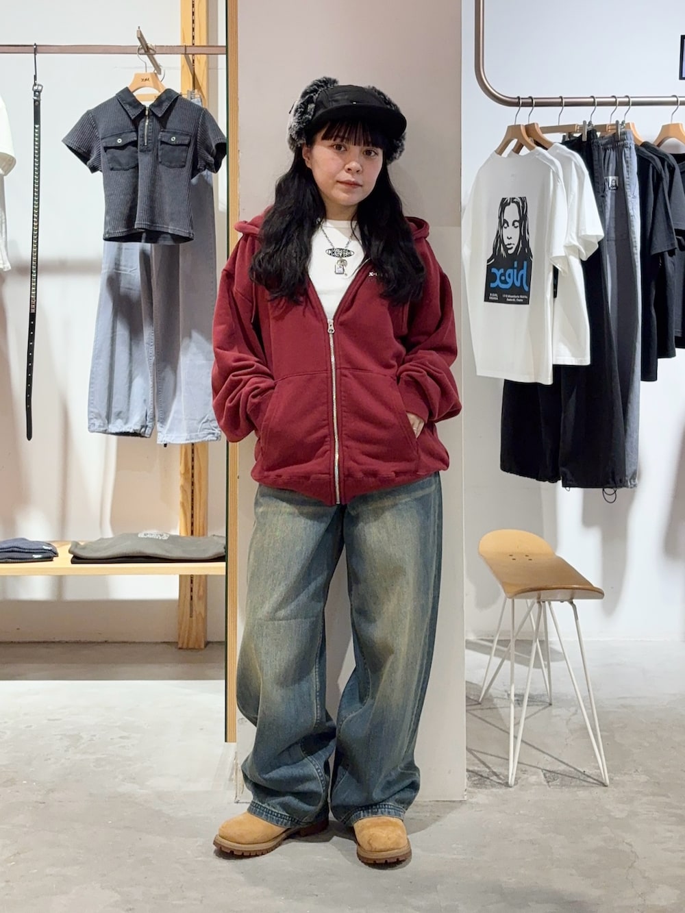 レッド系のパーカー、ブルー系のデニムパンツ、ブラック系のキャップを着用したレディースの秋コーディネートの2枚目の写真