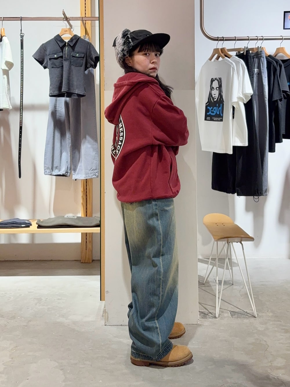 レッド系のパーカー、ブルー系のデニムパンツ、ブラック系のキャップを着用したレディースの秋コーディネートの3枚目の写真