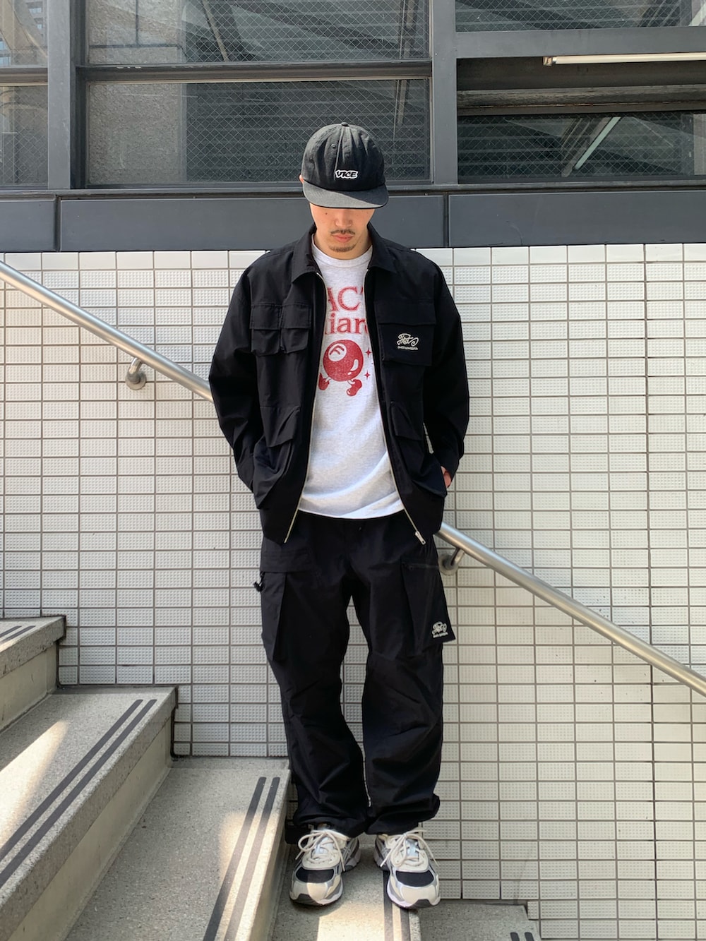 グレー系のTシャツ/カットソー、ブラック系のカーゴパンツ、ホワイト系のスニーカーを着用したメンズの春コーディネートの3枚目の写真