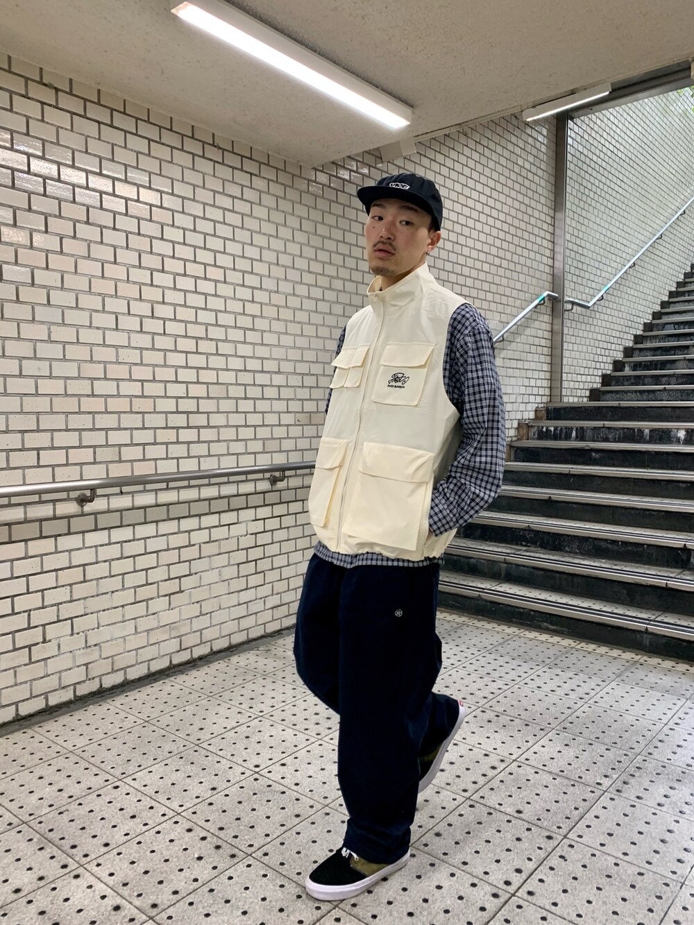 「WHO’S WHO gallery、レイヤードスタイル、ベスト、ベスト×シャツ、ベストコーデ、ベストスタイル、チノパン、VANS、キャップ、カジュアルコーデ、ストリート、チェックシャツ、シャツスタイル」｜「WHO'S WHO galleryのCOOPER FACTミリタリースタンドカラーベスト（ベスト、ホワイト系）」を使った、mitsuoさん（骨格ストレート・メンズ・176cm）の春コーディネートの3枚目の写真