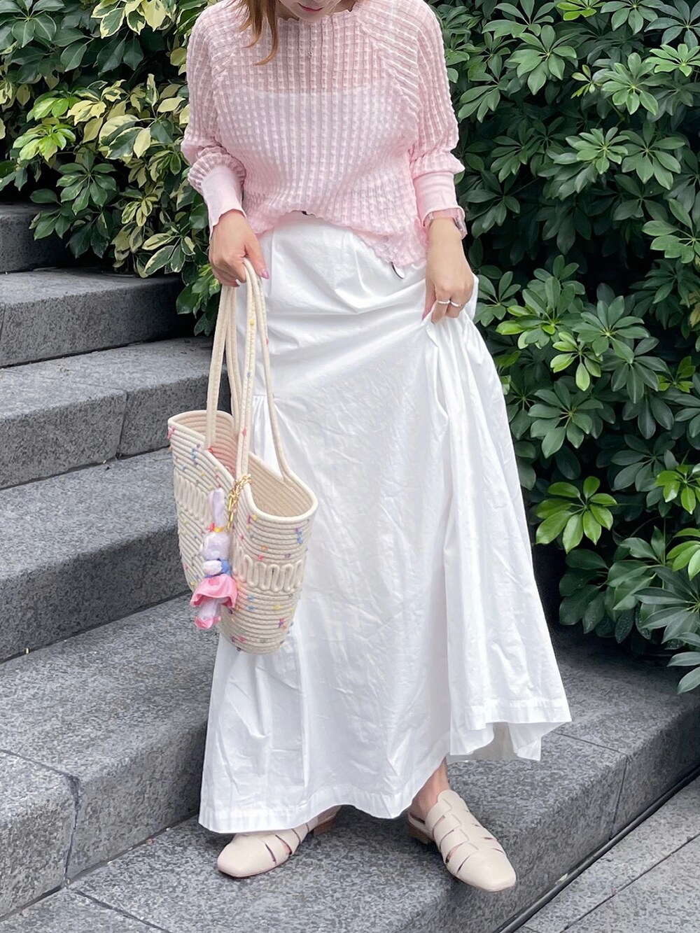 ピンク系のニット/セーター、ホワイト系のスカート、ホワイト系のサンダルを着用したレディースの夏コーディネートの3枚目の写真