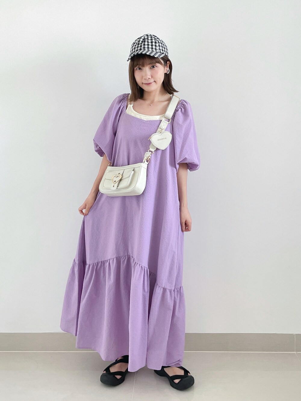 ベージュ系のワンピース、ブラック系のサンダル、ホワイト系のキャップを着用したレディースの夏コーディネートの3枚目の写真