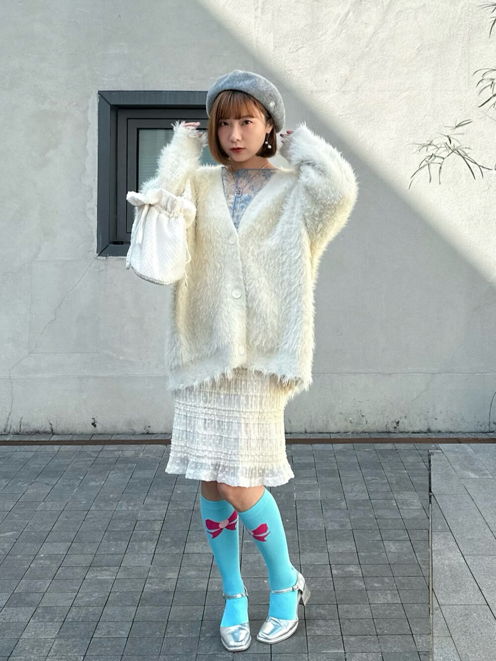 ブルー系のTシャツ/カットソー、ホワイト系のスカート、シルバー系のパンプスを着用したレディースの冬コーディネートの3枚目の写真