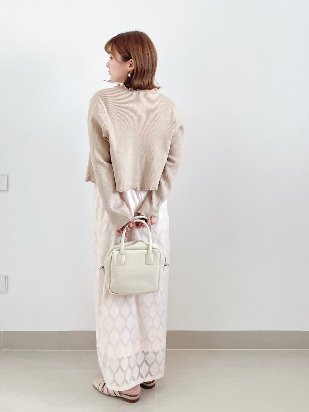 ホワイト系のハンドバッグ、ホワイト系のサンダルを着用したレディースの秋コーディネートの2枚目の写真