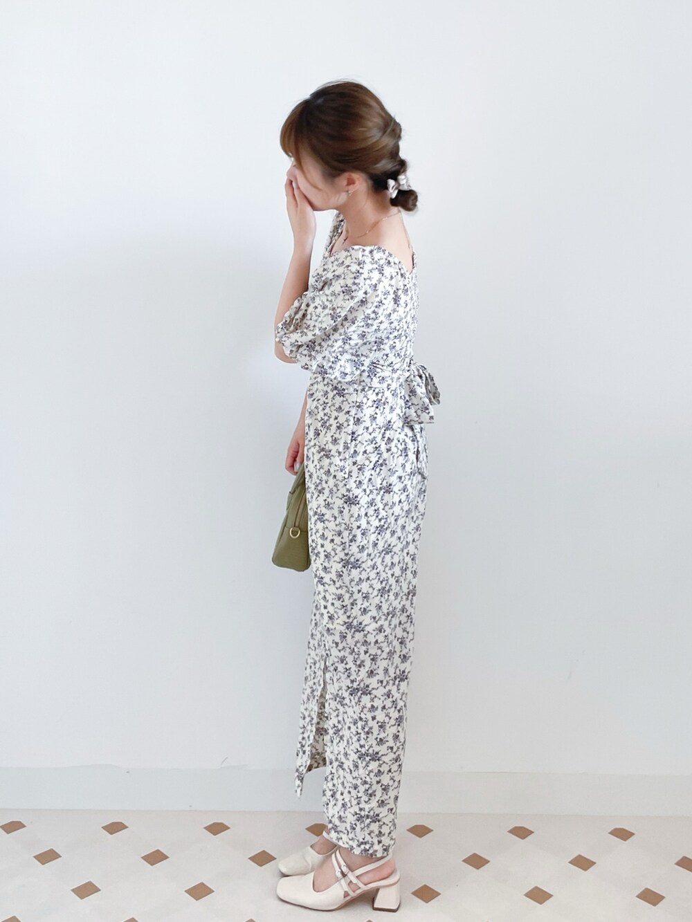 ホワイト系のワンピース、グリーン系のハンドバッグ、ホワイト系のパンプスを着用したレディースの夏コーディネートの2枚目の写真