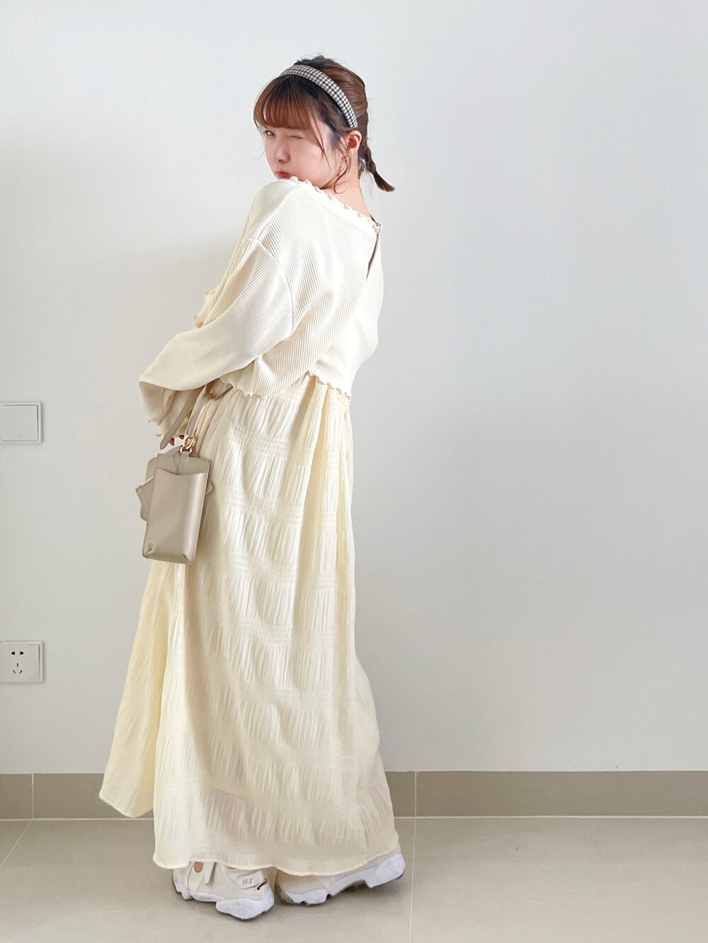 ホワイト系のワンピース、ベージュ系のサンダル、ホワイト系のバッグを着用したレディースの秋コーディネートの3枚目の写真