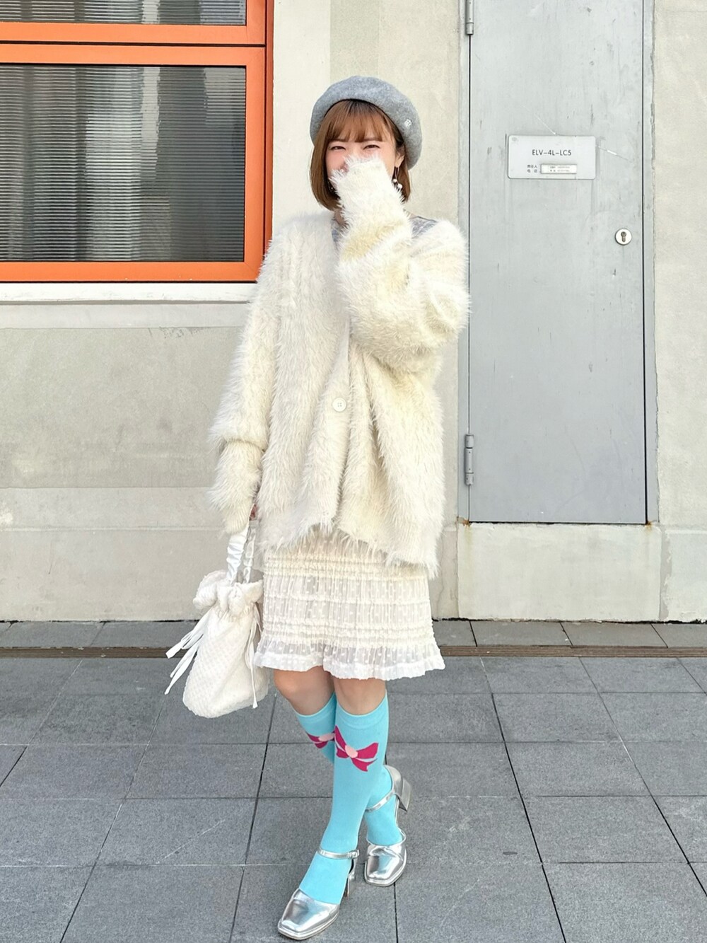 ブルー系のTシャツ/カットソー、ホワイト系のスカート、シルバー系のパンプスを着用したレディースの冬コーディネートの2枚目の写真