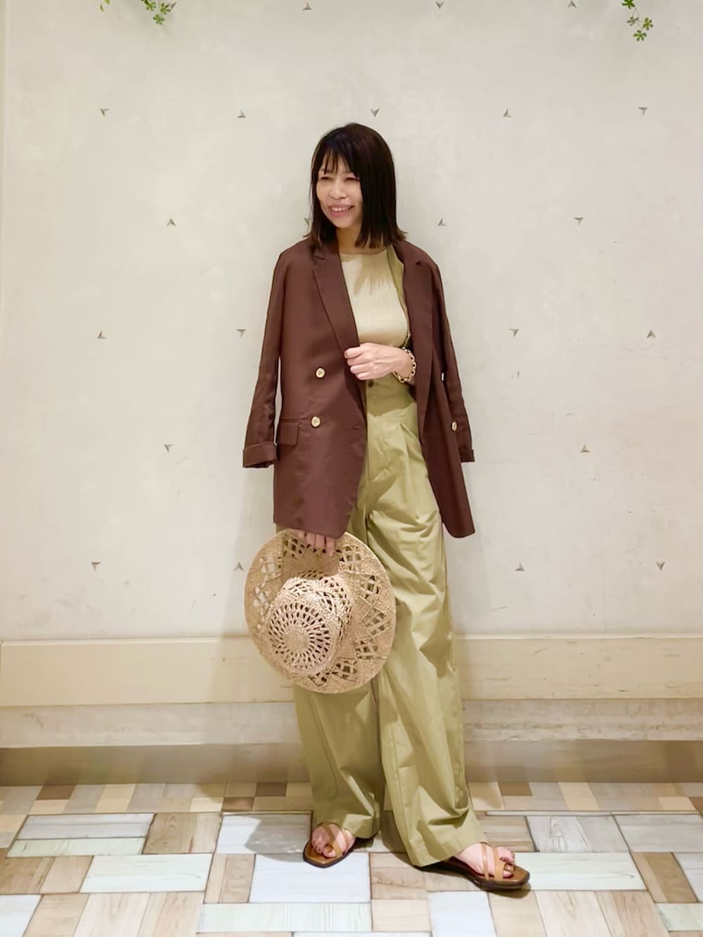 ブラウン系のテーラードジャケット、ゴールド系のタンクトップ、ベージュ系のその他パンツを着用したレディースの夏コーディネートの2枚目の写真