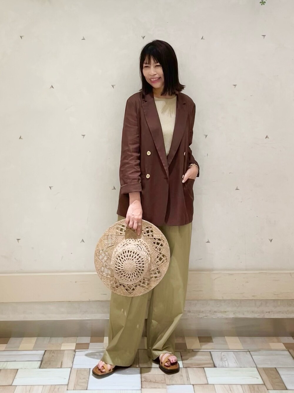 ブラウン系のテーラードジャケット、ゴールド系のタンクトップ、ベージュ系のその他パンツを着用したレディースの夏コーディネートの3枚目の写真