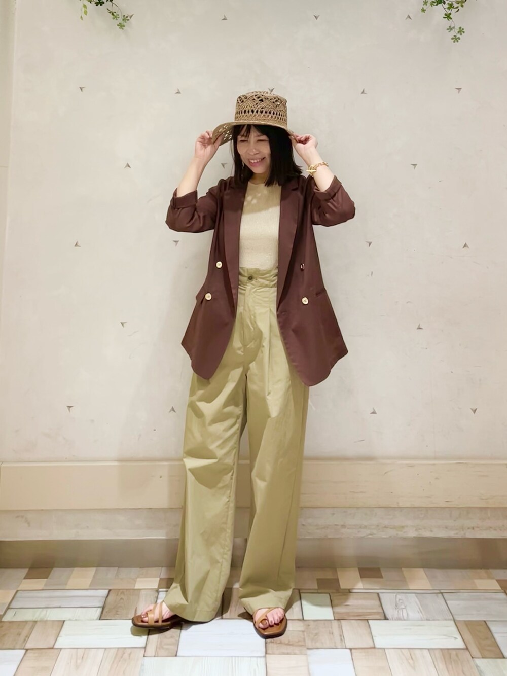 ブラウン系のテーラードジャケット、ゴールド系のタンクトップ、ベージュ系のその他パンツを着用したレディースの夏コーディネートの4枚目の写真