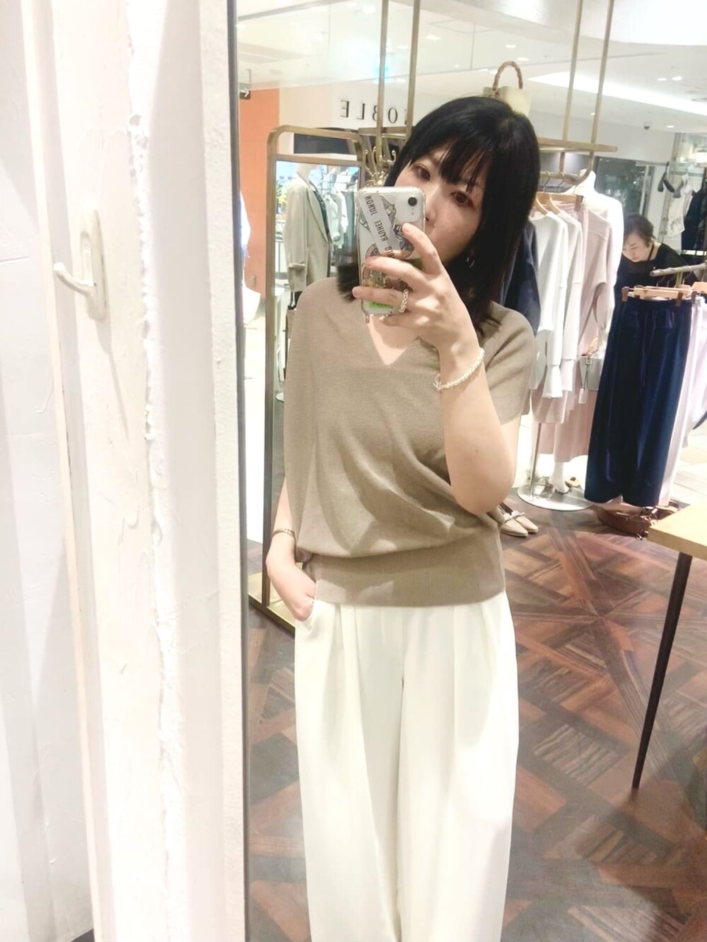 ベージュ系のニット/セーター、ホワイト系のスラックス、シルバー系のネックレスを着用したレディースの夏コーディネートの3枚目の写真