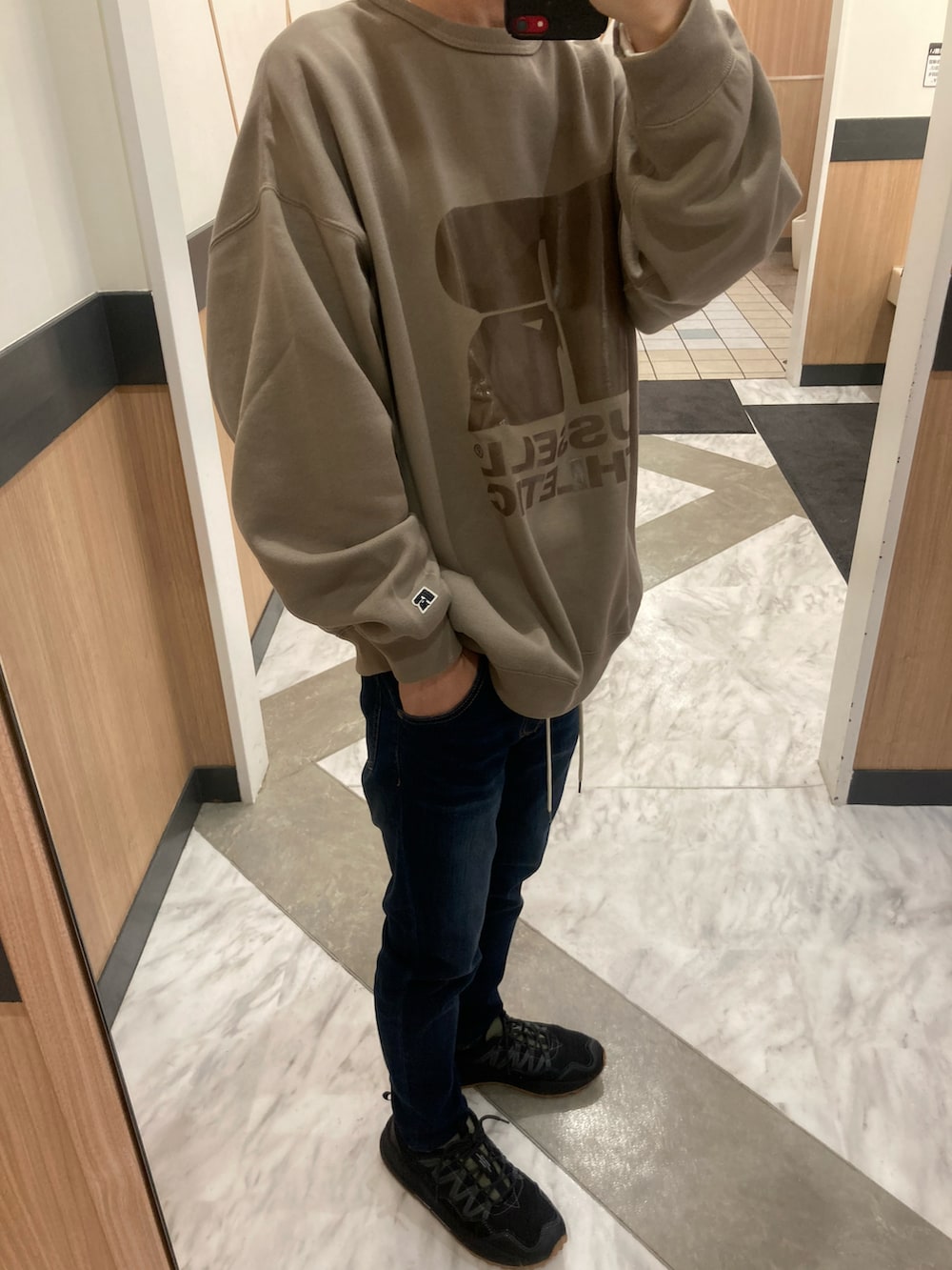 ブラック系のスニーカー、ブルー系のデニムパンツ、ベージュ系のスウェットを着用したメンズの冬コーディネートの2枚目の写真