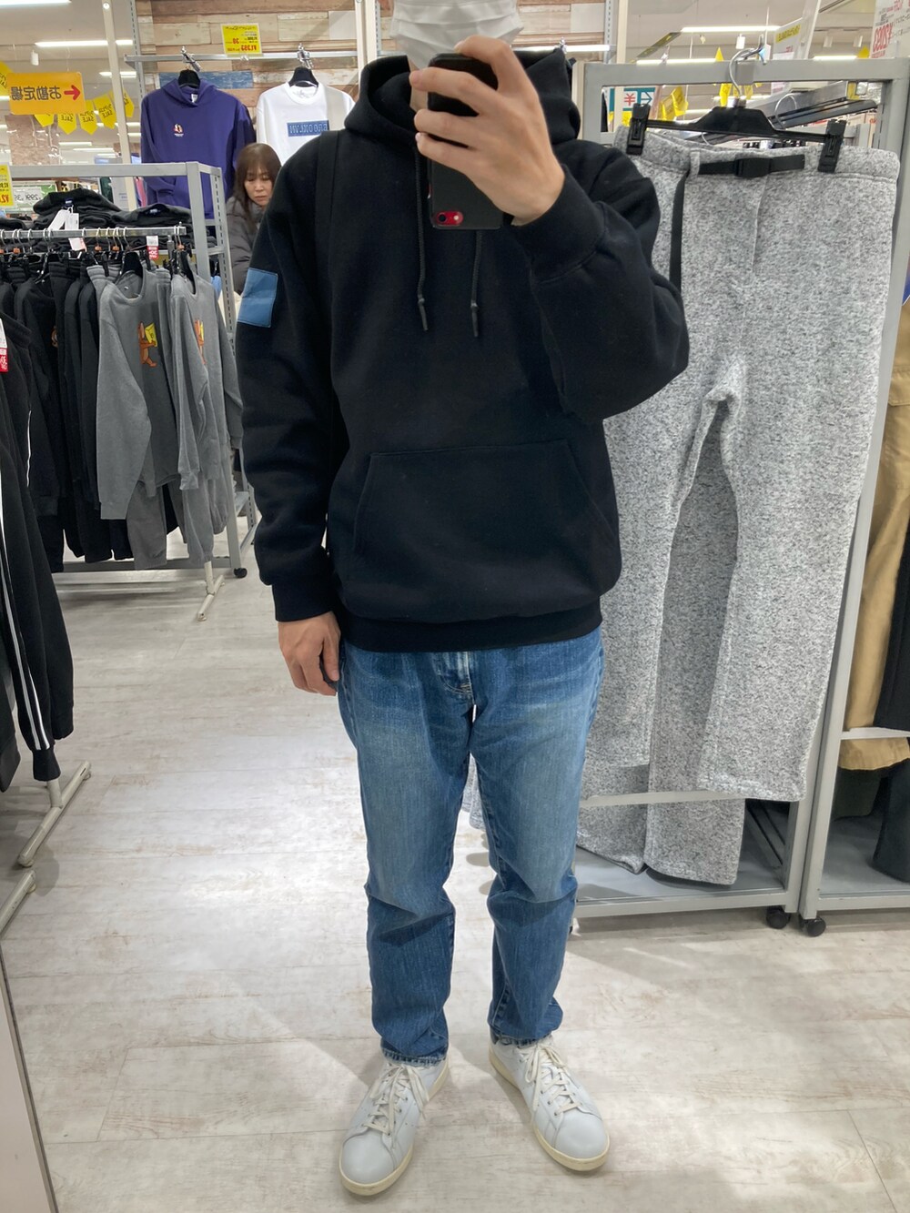 ホワイト系のスニーカー、ブルー系のデニムパンツ、ブラック系のパーカーを着用したメンズの冬コーディネートの2枚目の写真