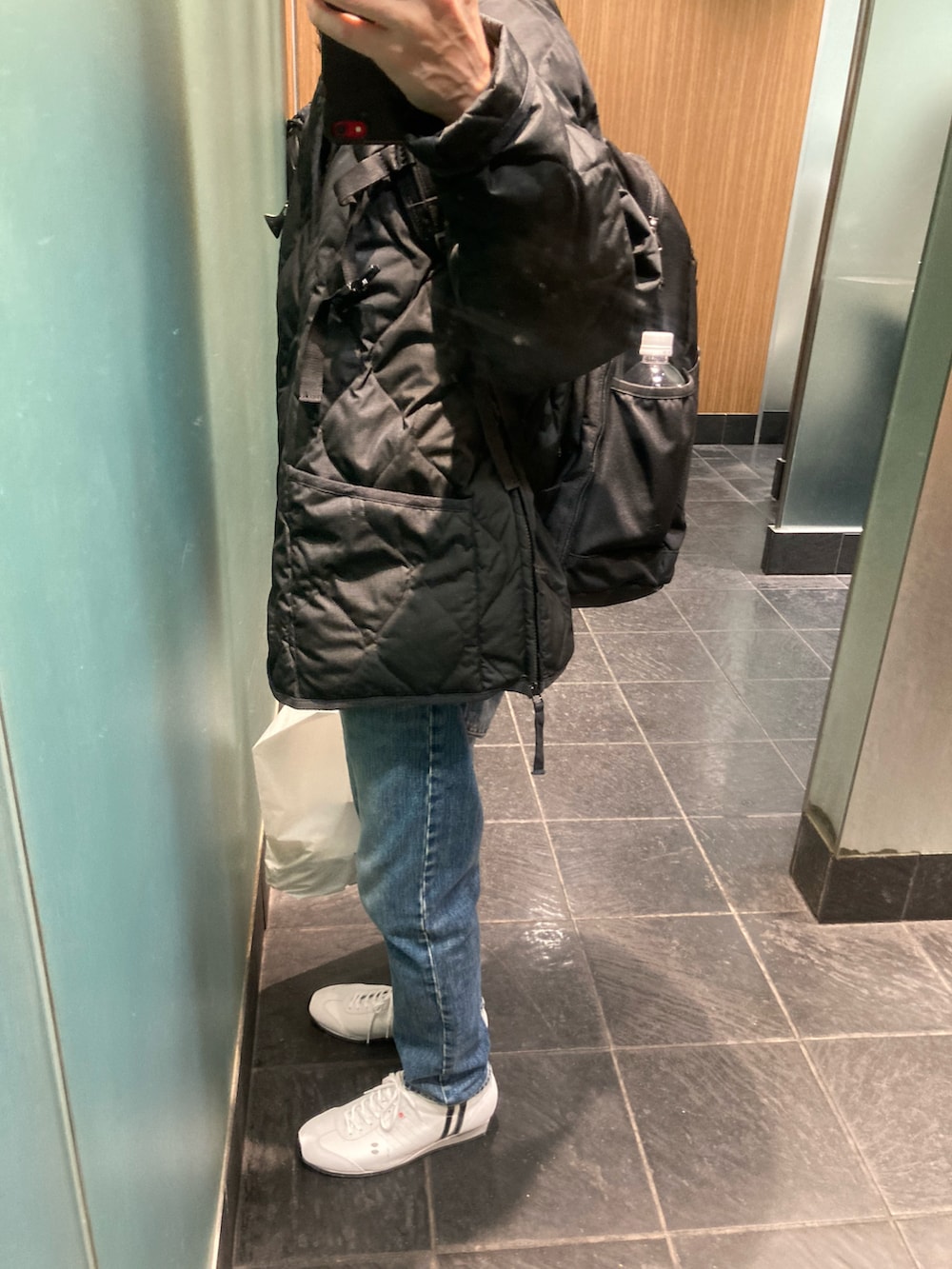 ホワイト系のスニーカー、ブルー系のデニムパンツ、ブラック系のダウンジャケット/コートを着用したメンズの冬コーディネートの2枚目の写真