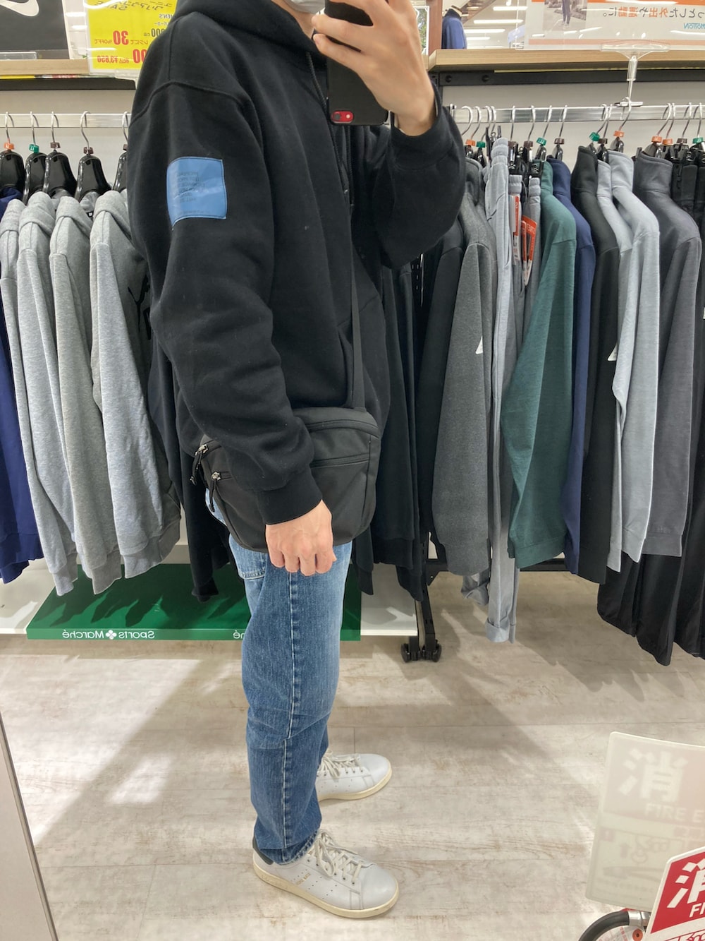 ホワイト系のスニーカー、ブルー系のデニムパンツ、ブラック系のパーカーを着用したメンズの冬コーディネートの3枚目の写真