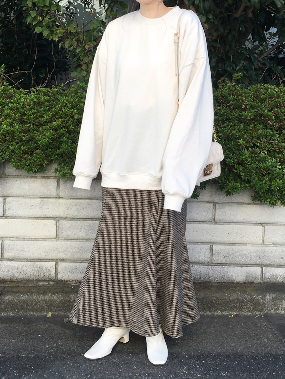 ホワイト系のスウェット、ブラウン系のスカート、ホワイト系のブーツを着用したレディースの秋コーディネートの2枚目の写真